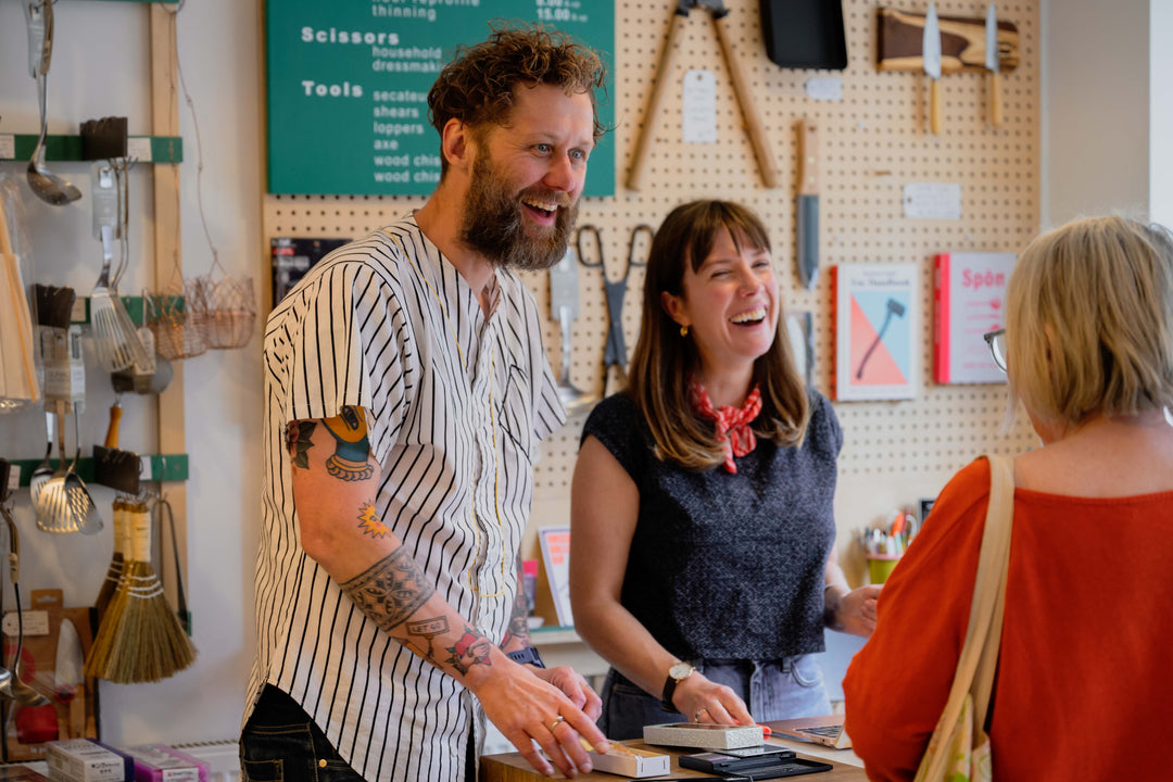 Couple ina kitchenware shop laughing with customer