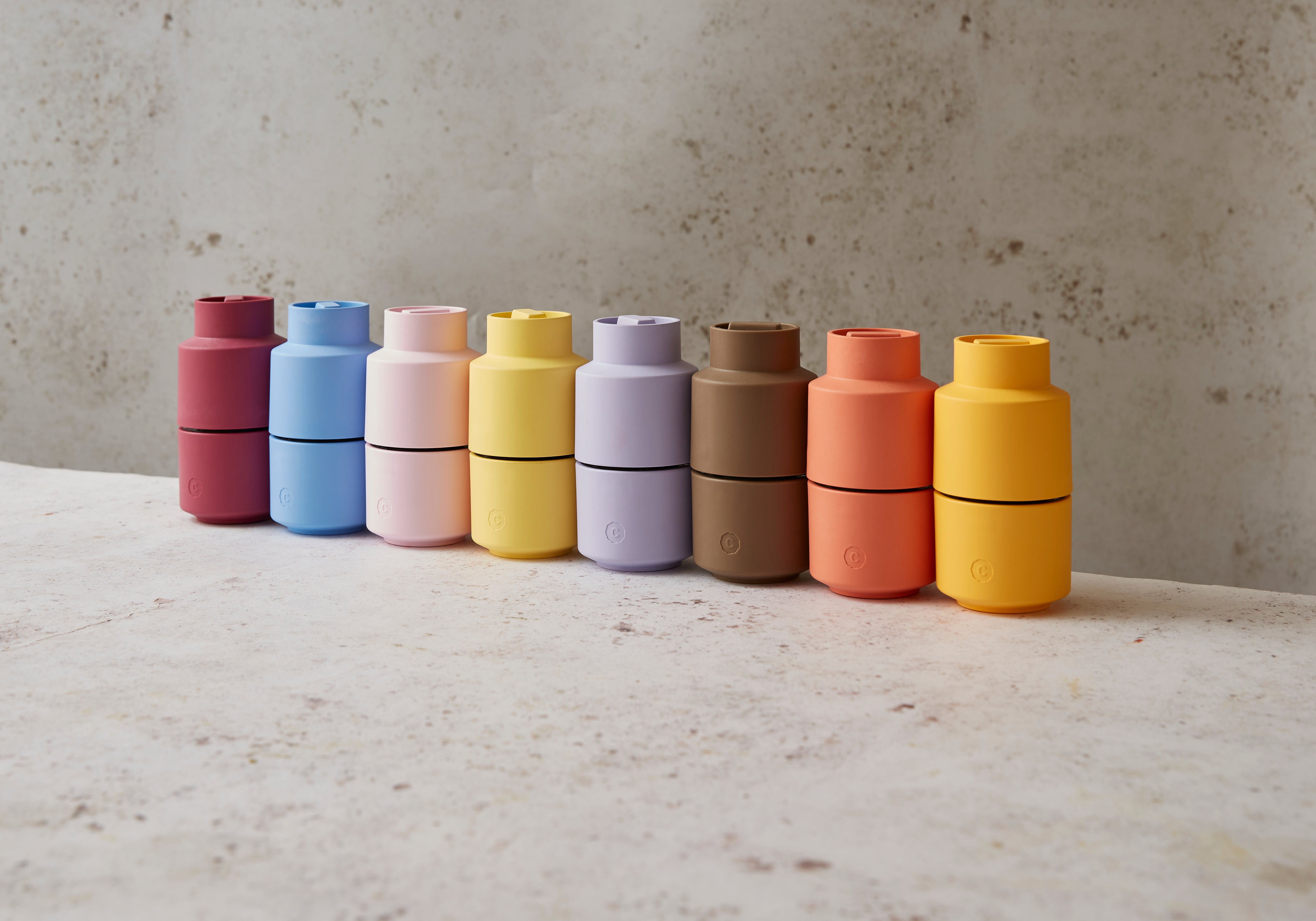 Row of colourful CrushGrind pepper mill grinders on a neutral background