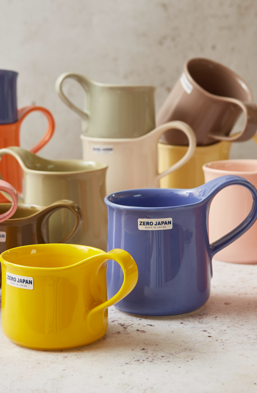 Colorful mugs with 'Zero Japan' label on a textured surface
