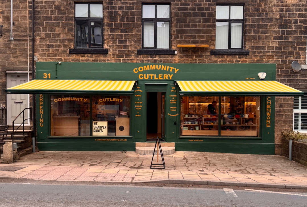 Community Cutlery store with green and yellow facade on a brick building.